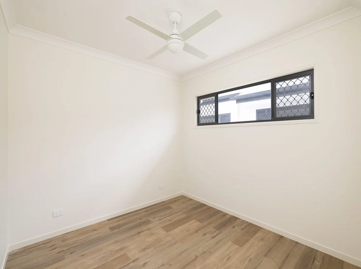 Bright bedroom with fan and floorboards in disability-friendly Beatty Road unit.