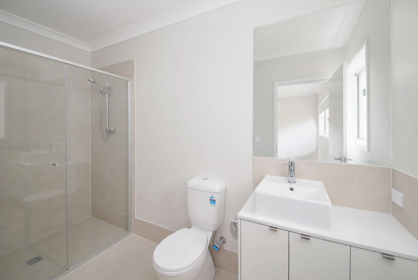 Modern bathroom in Logan home at 8 Lilly Lane with shower, vanity, and toilet.