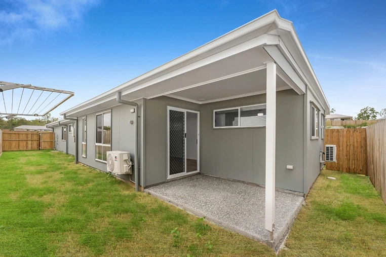 Back entry view of 1/7 Loch Way duplex in Brassall with covered patio and grassed yard.