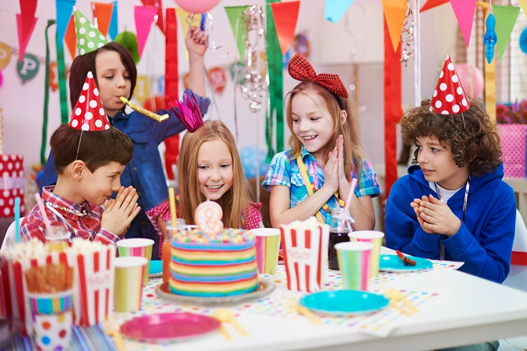 Children celebrating a colourful kids’ birthday party with cake, balloons, and decorations, joyful and inclusive party planning inspiration.