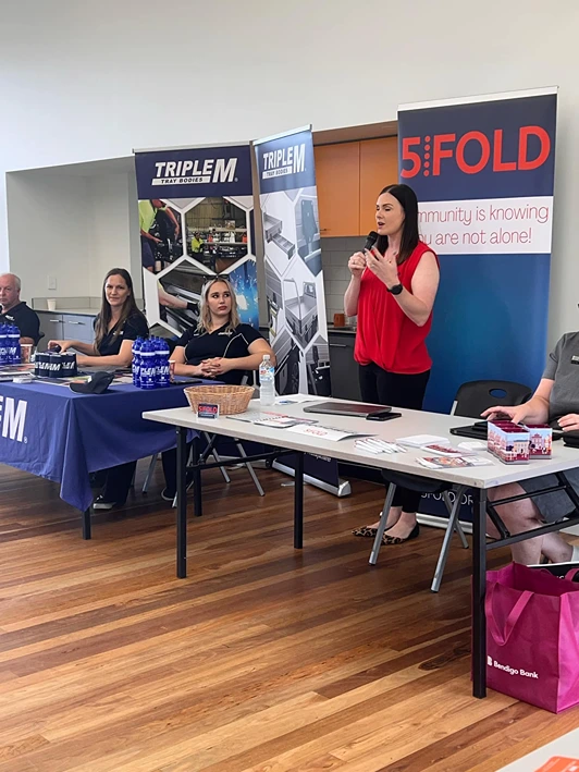 YMC expo booth inside community hall with display tables and attendees.