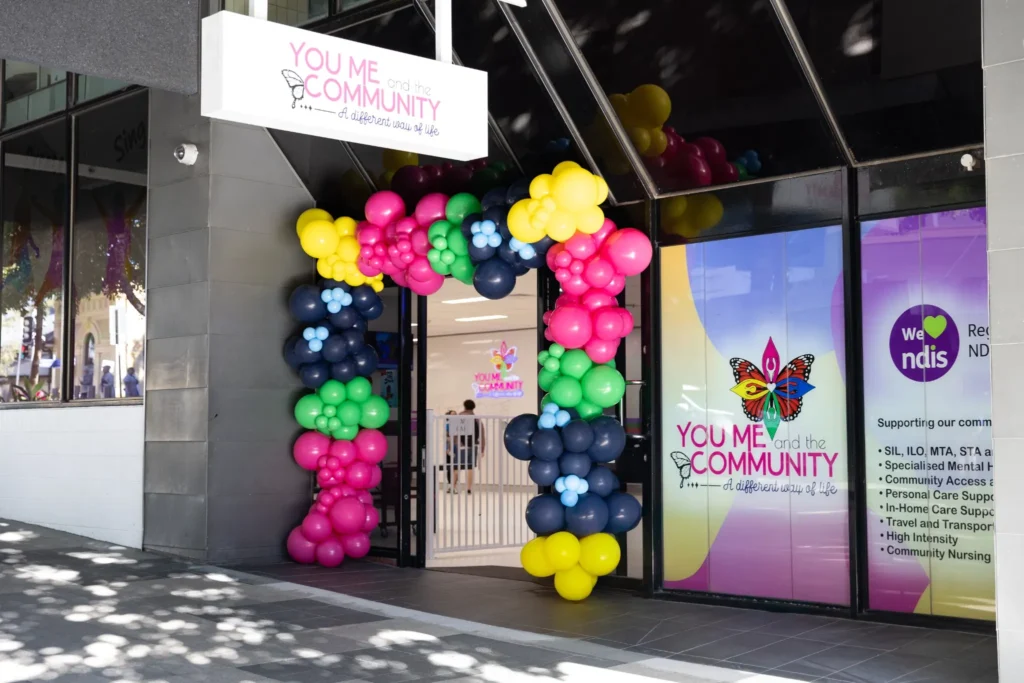 You Me & Community entrance at The Legacy Hub in Ipswich with colourful balloon display and inclusive community hub signage