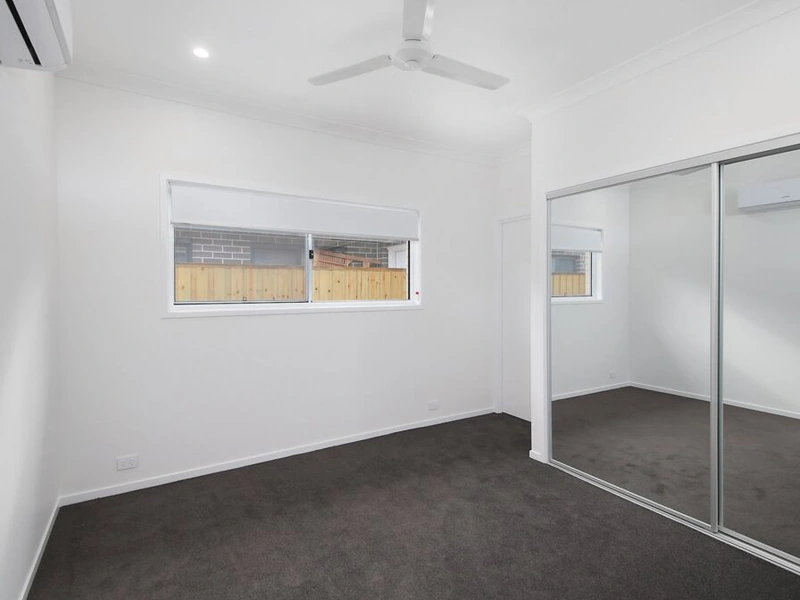Bright bedroom with mirrored wardrobe, ceiling fan and carpet flooring at Logan Reserve QLD 4133 property.