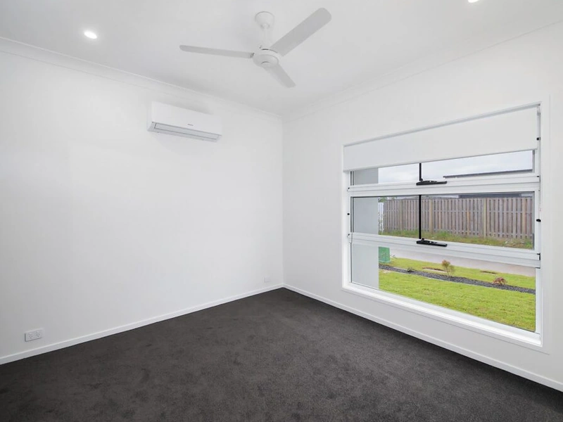 Carpeted bedroom with large window, air conditioning and ceiling fan at Logan Reserve QLD 4133 property.