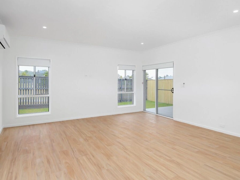 Bright open living room with timber flooring, large windows and sliding door at Logan Reserve QLD 4133 property.