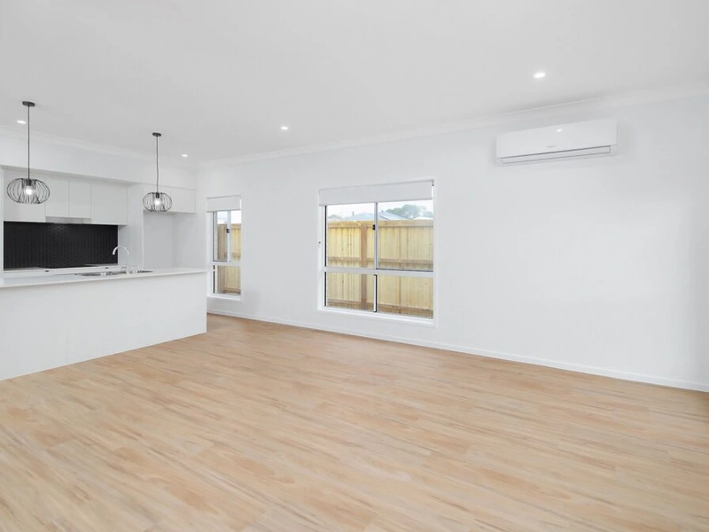 Open plan living and kitchen area with timber flooring, large windows and air conditioning at Logan Reserve QLD 4133 property.