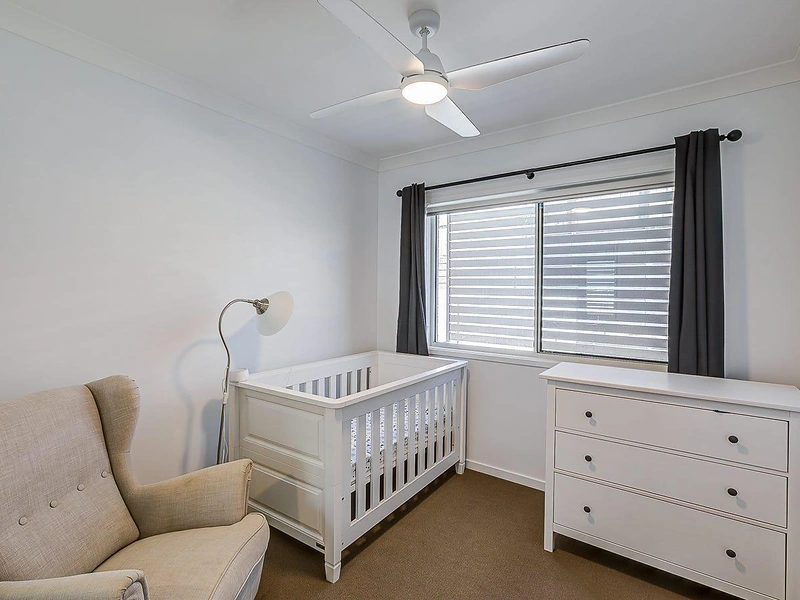 Bedroom with window, ceiling fan and cot in Greenbank