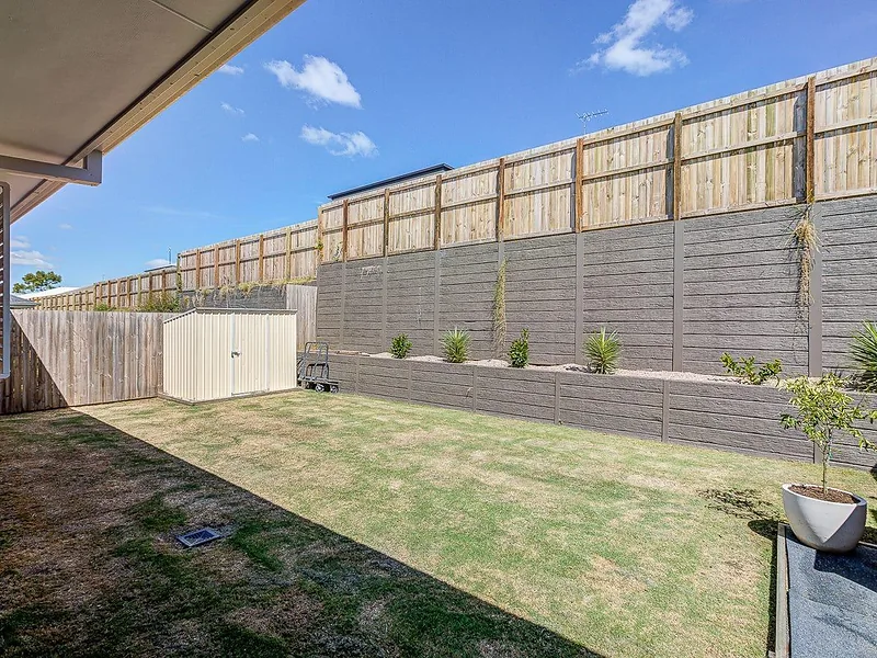 Fenced backyard with lawn and garden area in Greenbank