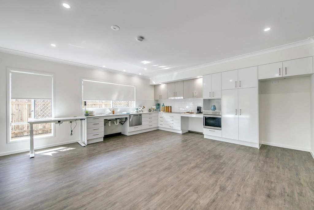 Modern accessible kitchen with white cabinetry and open floor space in Ormeau